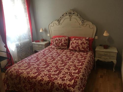 a bedroom with a bed with a red comforter and pillows at El telar de María in Ávila