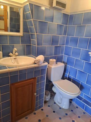 La salle de bains est pourvue de carrelage bleu, de toilettes et d'un lavabo. dans l'établissement Les Roses Trémières, à Bargème