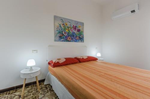 a bedroom with a bed with red pillows and a painting at Cagliari Comfy Apartment with Terrace & Netflix! in Selargius