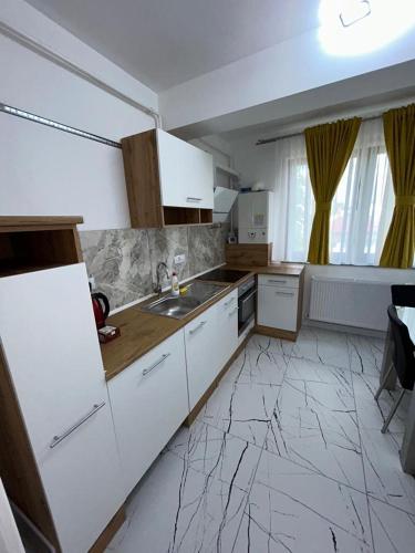a kitchen with white cabinets and a sink at Cozy Aparthotel - Central City Suceava in Suceava