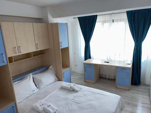 a bedroom with a bed and a desk and a window at Cozy Aparthotel - Central City Suceava in Suceava
