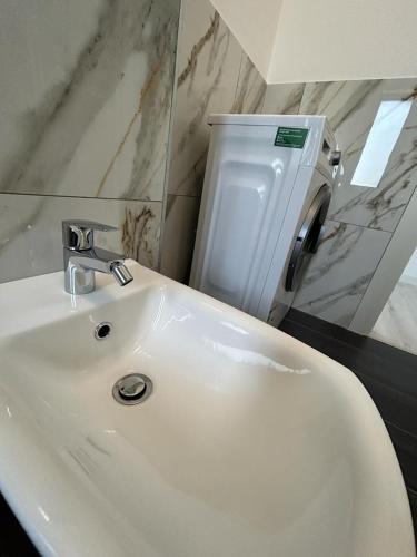 a bathroom with a white sink and a soap dispenser at Marvellous Aparthotel with Master Apartments Suceava in Suceava