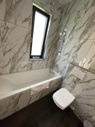 a bathroom with a tub and a toilet and a window at Marvellous Aparthotel with Master Apartments Suceava in Suceava