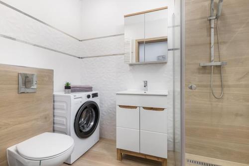 a bathroom with a washing machine and a toilet at Bm Apartamenty w Centrum Szczecin in Szczecin