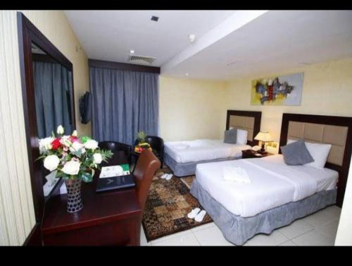 ドバイにあるcomfort zone for accommodationのベッド2台、テーブル(花付)が備わる客室です。
