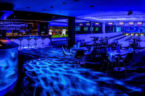 a bar with tables and chairs in a room with blue lights at Hotel Ponteo - Activity Park in Bratislava