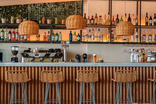 a bar with three bar stools and bottles of alcohol at Kenta Beach Hotel in Agios Ioannis Pelio
