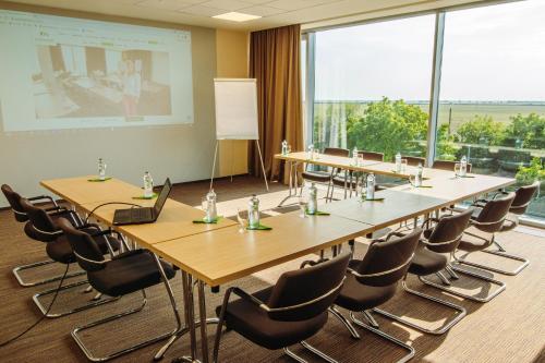 a conference room with tables and chairs and a projection screen at Hotel Ponteo - Activity Park in Bratislava