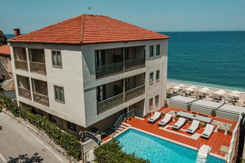 a building with a swimming pool next to the ocean at Kenta Beach Hotel in Agios Ioannis Pelio