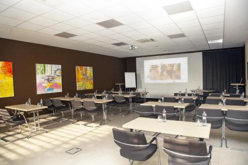 a conference room with tables and chairs and a projection screen at Hotel Ponteo - Activity Park in Bratislava