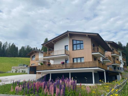 a apartment building with a balcony and purple flowers at Moderne Kaminstube in Ramsau am Dachstein