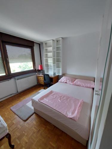 a bedroom with a bed and a desk and a window at Apartman LAURA in Zagreb