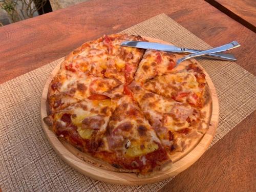 a pizza sitting on top of a wooden plate on a table at The Gallery Hotel Nai Harn in Nai Harn Beach