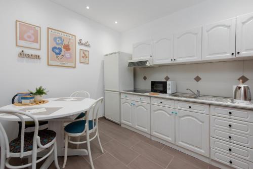 uma cozinha com armários brancos e uma mesa com cadeiras em Studio apartment Lu em Rupa