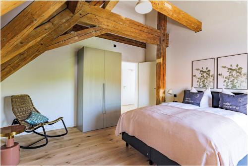 a bedroom with a large bed and a chair at Limehome Dachau Konrad-Adenauer-Str in Dachau