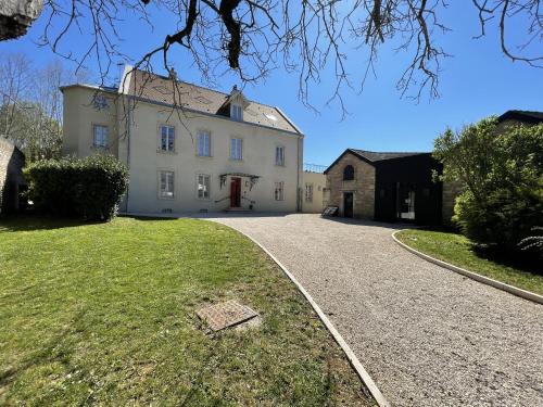 une grande maison blanche avec une allée. dans l'établissement Manoir de Villamont, à Savigny-lès-Beaune