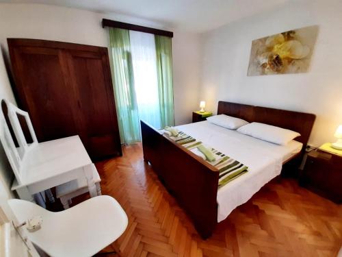ein Schlafzimmer mit einem großen Bett und einem weißen Stuhl in der Unterkunft Vacation House Calluna in Vrisnik