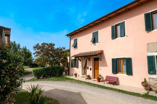 a pink building with green shutters and a bench at Casa vacanze Santa Maria in Certaldo