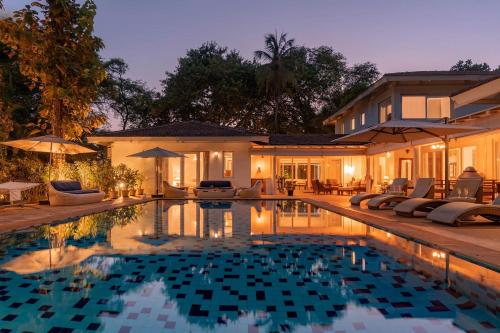 a swimming pool in front of a house at Hamptons Charm by StayVista Luxury 5BR with Pool, lawn & table tennis in Alibaug