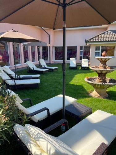 un patio con sillas, una sombrilla y una fuente en Spa & Wellness Hotel Orchidea, en Veľký Meder