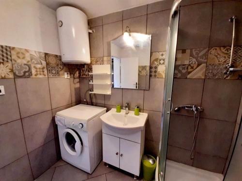 ein Badezimmer mit einer Waschmaschine und einem Waschbecken in der Unterkunft Vacation House Calluna in Vrisnik