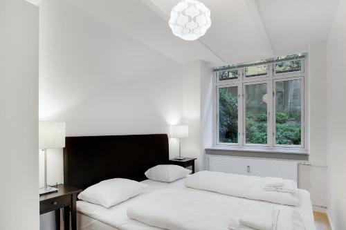 a white bedroom with a bed and a window at City Center Apartments 739 in Copenhagen