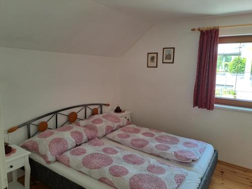 Schlafzimmer mit einem Bett mit rosa Kissen und einem Fenster in der Unterkunft Ferienhaus Sapplerhof in Millstatt