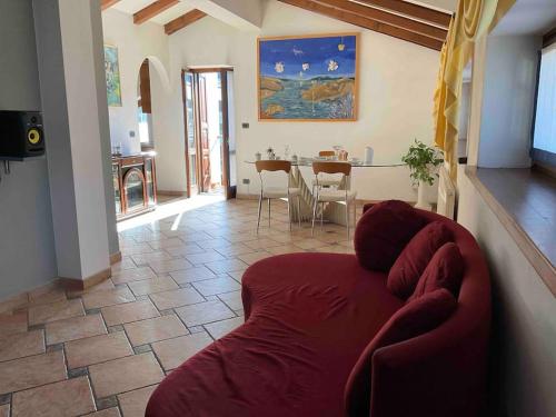 a living room with a red couch and a table at CASA FILAFERRO - VIA LOMBARDIA 4 MOGGIO UDINESE in Moggio Udinese