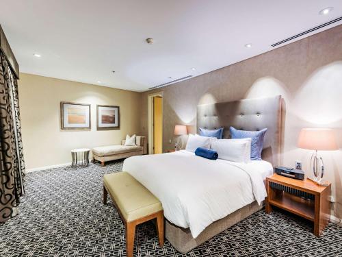 a bedroom with a large bed and a living room at Sofitel Sydney Wentworth in Sydney