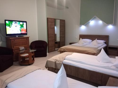 a hotel room with two beds and a flat screen tv at Pensiunea Casa Rusu in Baia Mare