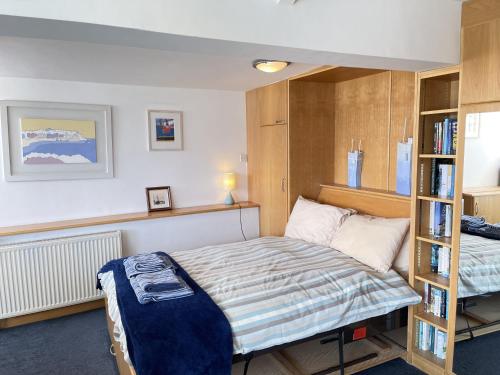 a bedroom with a bed and a book shelf at Crows Nest - panoramic views of St Ives harbour in St Ives