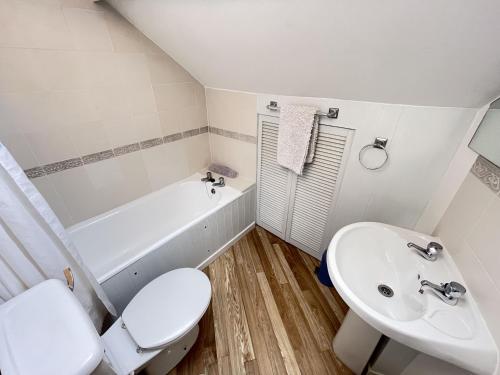 a white bathroom with a toilet and a sink at Crows Nest - panoramic views of St Ives harbour in St Ives