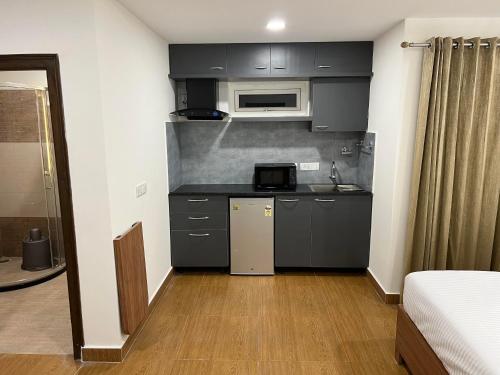 una pequeña cocina con armarios negros y microondas en Palladium Luxury Suites Financial District Unit I, en Hyderabad