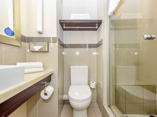 a bathroom with a toilet and a shower at Mercure Johannesburg Randburg in Johannesburg