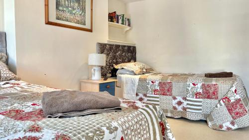 a bedroom with two beds and a table with a lamp at 3 Bedroom Character Townhouse on Edge of Blackdown Hills in Wellington