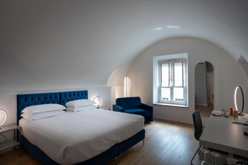 a bedroom with a bed and a blue chair and a desk at Le Stanze Del Savonarola in Ferrara