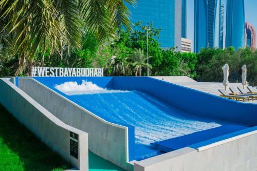 a pool with blue water in a resort with buildings at Radisson Blu Hotel & Resort, Abu Dhabi Corniche in Abu Dhabi