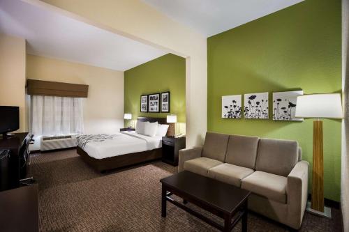 Sleep Inn & Suites في فلدوستا: غرفه فندقيه بسرير واريكه