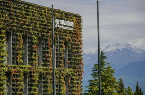 a building covered in ivy with a mountain in the background at Tsinandali Estate, A Radisson Collection Hotel in Tsinandali
