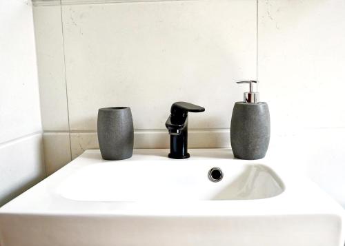 a bathroom sink with a faucet and two cups at Electra apartment Agia Triada in Agia Triada