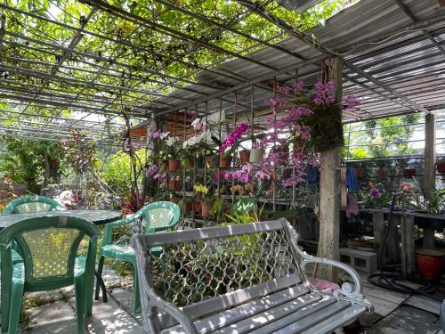 ein Gewächshaus mit einer Bank, Tischen und Blumen in der Unterkunft Garden Hostel in Minxiong