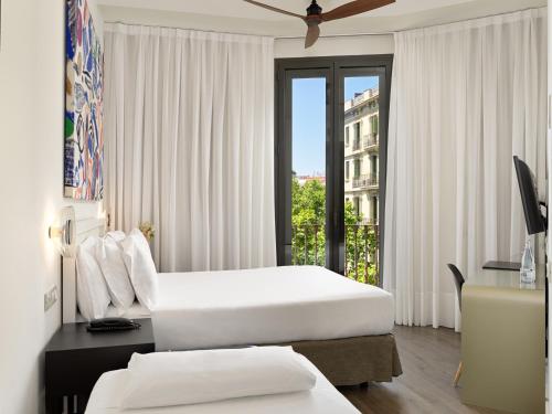 a hotel room with two beds and a window at H10 Casanova in Barcelona