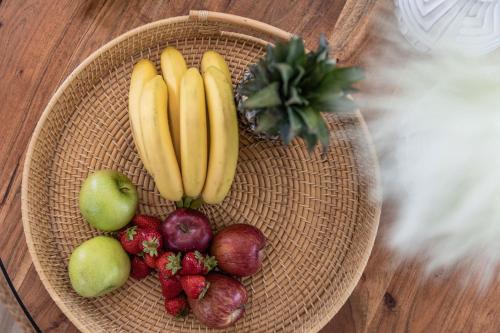 a basket of fruit with bananas apples and strawberries at Arsenis Luxury Villas in Plaka