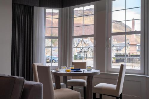 a table and chairs in a room with windows at Dunalastair Hotel Suites in Kinloch Rannoch