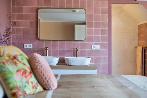 a bedroom with a pink tiled wall with a mirror at Enschede81 in Enschede