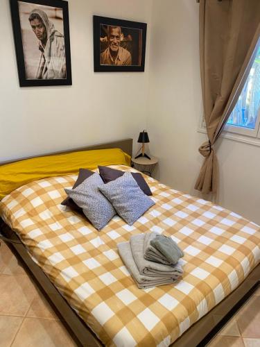 uma cama com um cobertor xadrez e almofadas em Rez de Jardin Villa Cagnes Sur Mer. em Cagnes-sur-Mer
