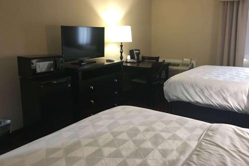 a hotel room with two beds and a desk with a television at Wyndham Garden Dover in Dover
