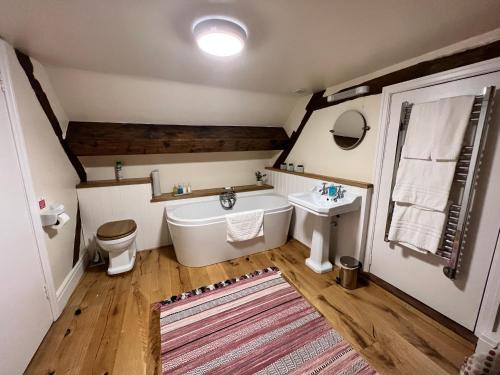 a bathroom with a tub and a toilet and a sink at The Harp Inn in Old Radnor