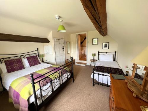 a bedroom with two beds and a desk with a lamp at The Harp Inn in Old Radnor
