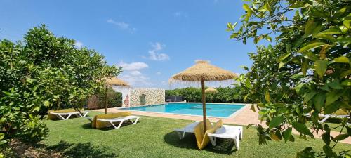 a swimming pool with two chairs and an umbrella at Quinta dos I's - Algarve in Algoz